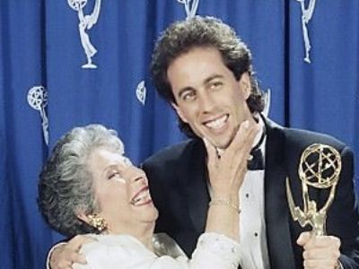 Jerry Seinfeld is showing his award and Betty Seinfeld is grabbing his chin.
